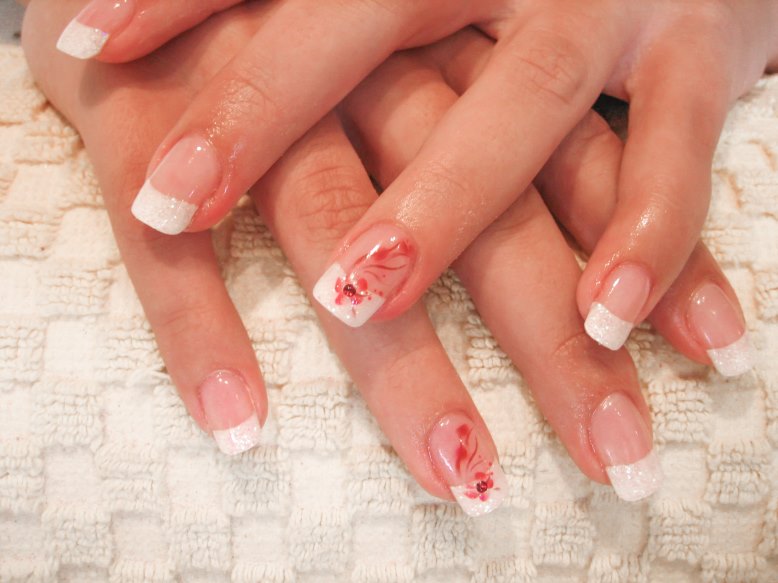 French-Nails mit weißem Glitzer und Blumenmotiv verziert mit einem Strassstein